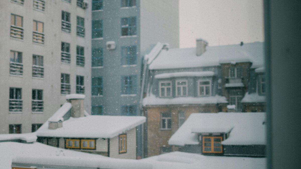 Snowy City View From a Window, Showcasing White Rooftops - Impact of Winter Weather on Commercial Roofs