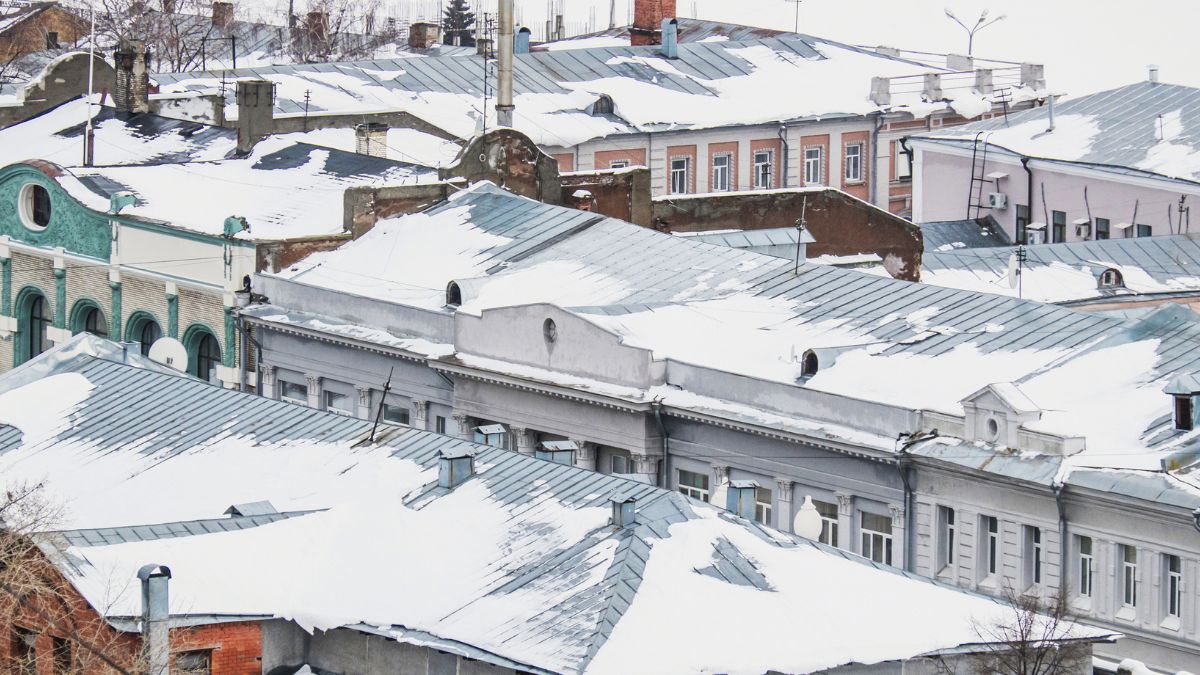 Old buildings with snow-covered roofs emphasize the need for immediate winter roofing services in Illinois to prevent damage